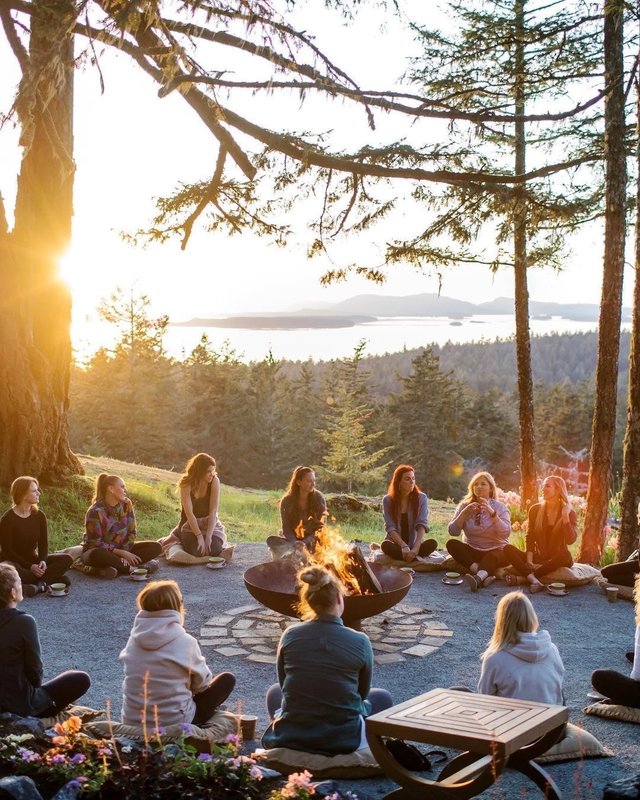 Group gathering around campfire at sunset
